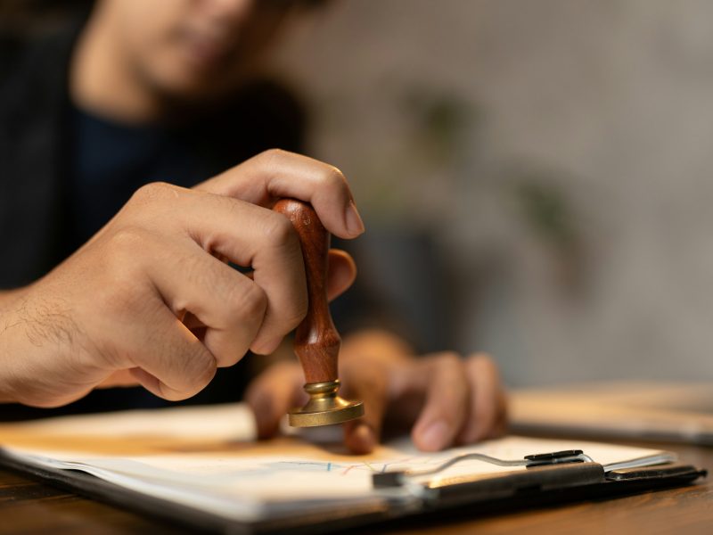 hand stamping with approved stamp on certificate document public paper at desk, notary or business